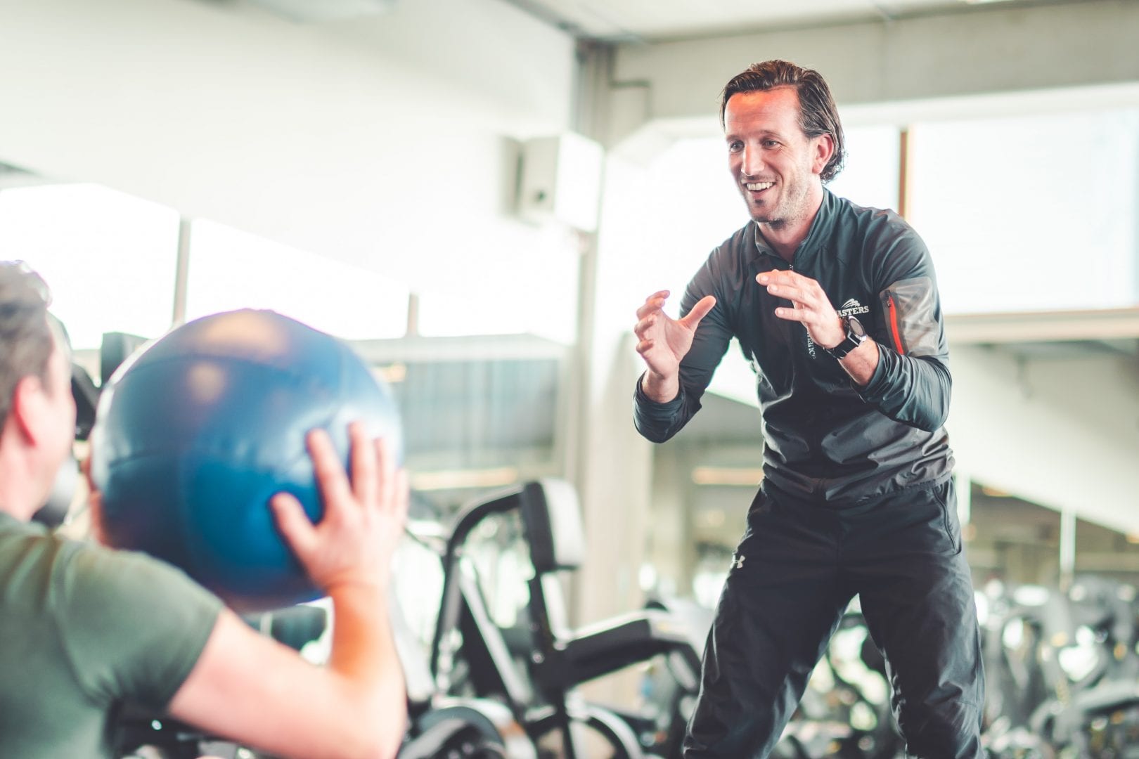 man gooit fitness bal naar coach