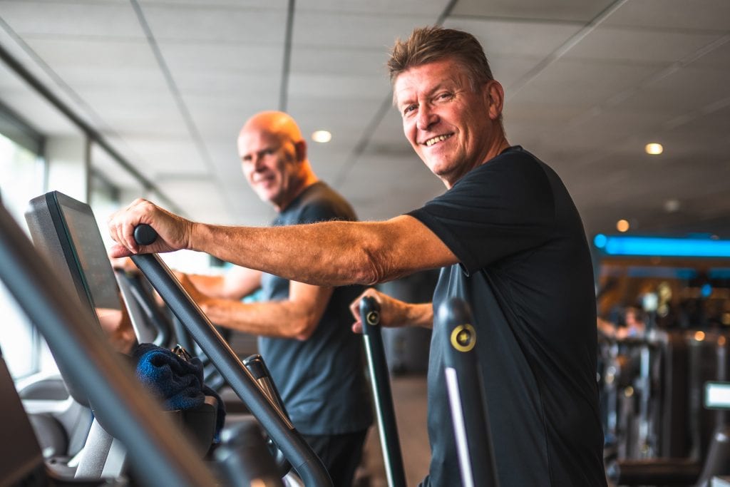 lachende mannen op crosstrainer