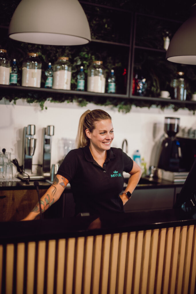 lachende medewerkster mylife achter de bar