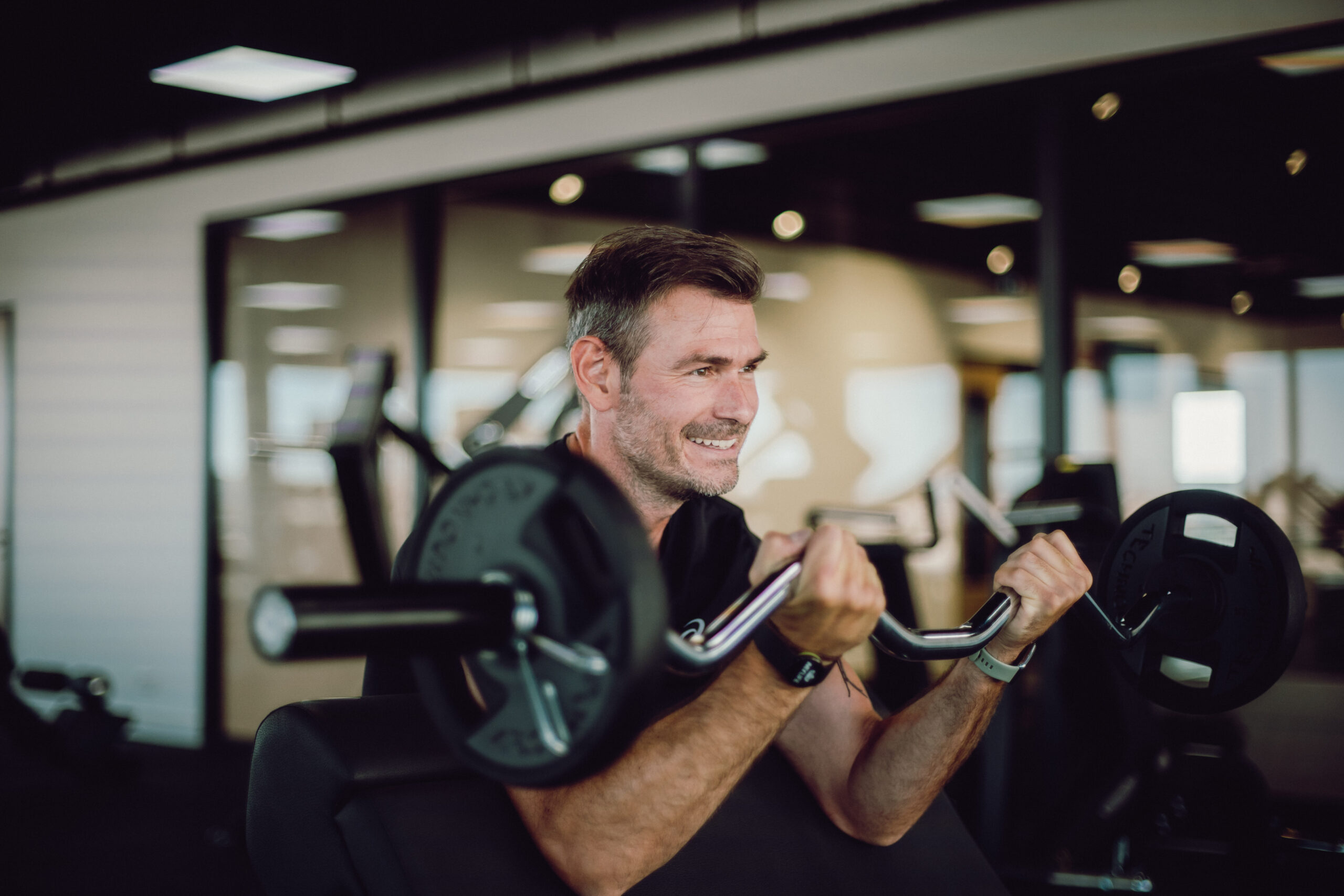man met barbell in fitness ruimte aan het trainen